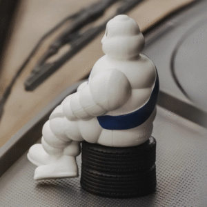 Michelin figure sitting on car tires placed on a dashboard.