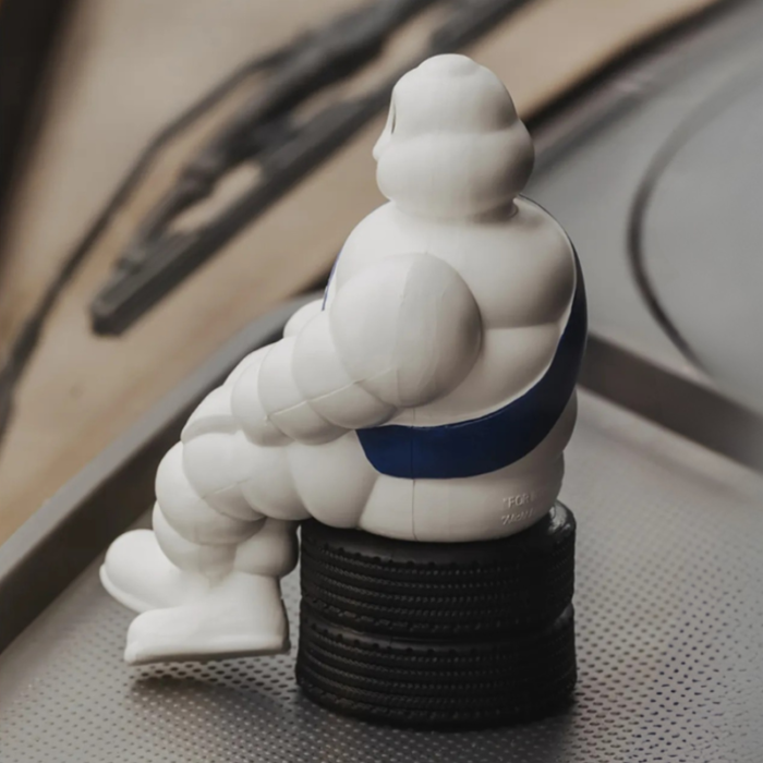 Michelin Man sitting on tires placed on a dashboard.